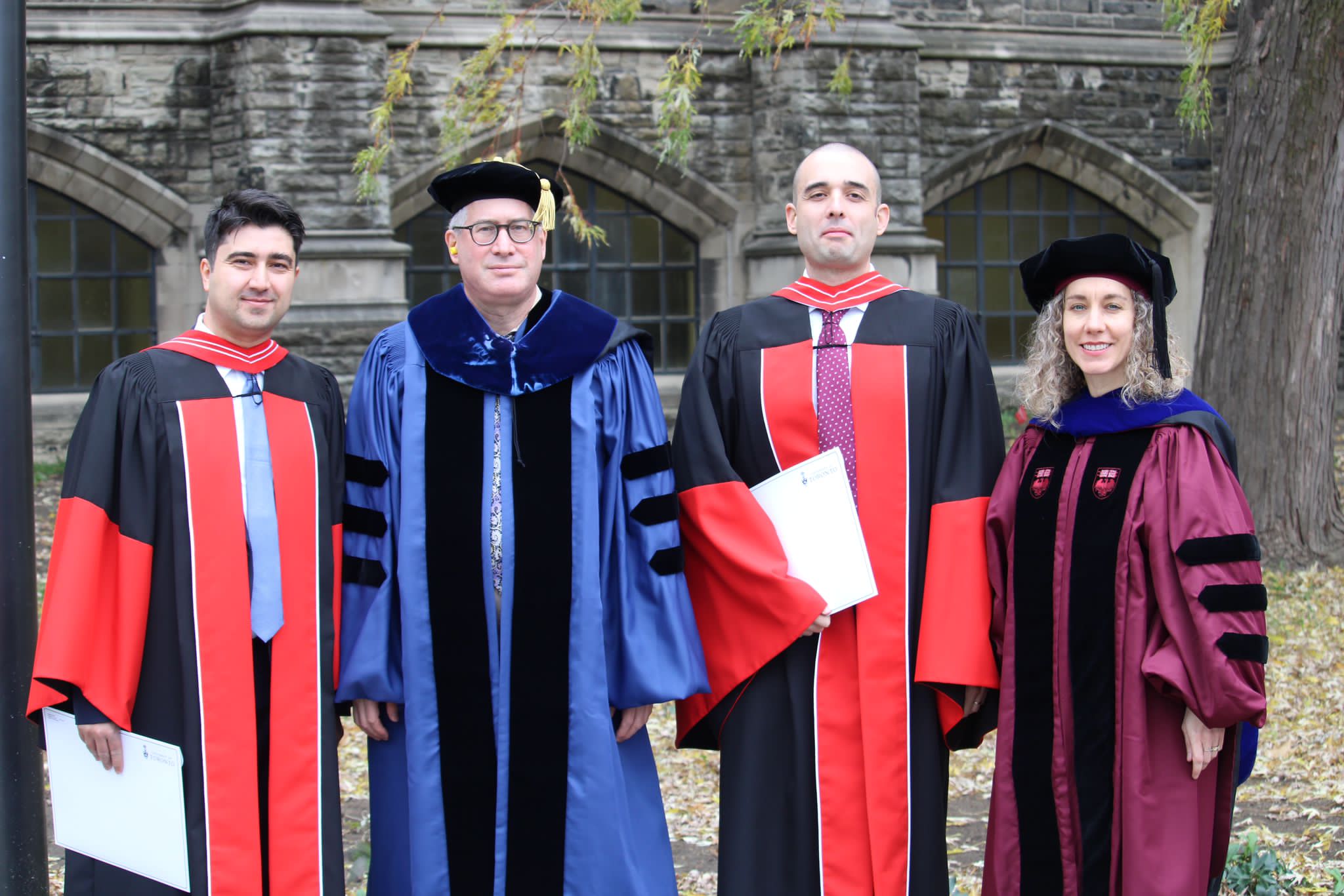 Robed graduates and professors pose outside Convocation Hall