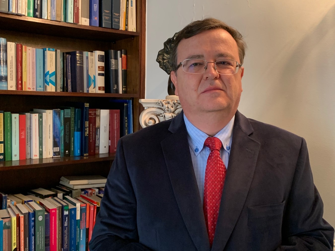 Judge Alejandro Ramelli Arteaga seated in front of bookshelves