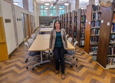 Librarian Danielle Van Wagner leans against one of the new study tables  at the CrimSL library