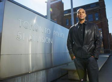 Professor Akwasi Owusu-Bempah stands next to Toronto Police Services 51 Division station sign